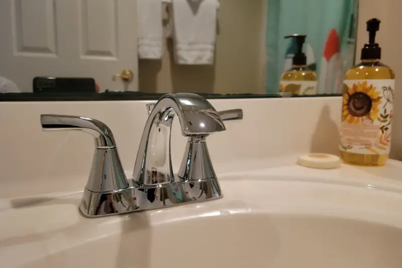 A bathroom sink featuring a modern faucet and a sleek soap dispenser