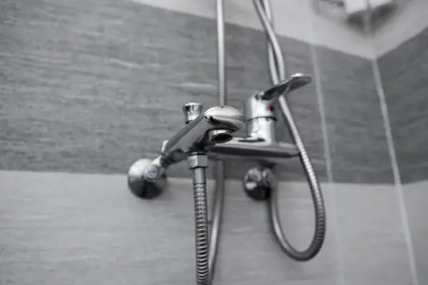 Modern designer tap and shower in bathroom. Closeup of chrome shower, faucet, in the bathroom covered decorative ceramic.